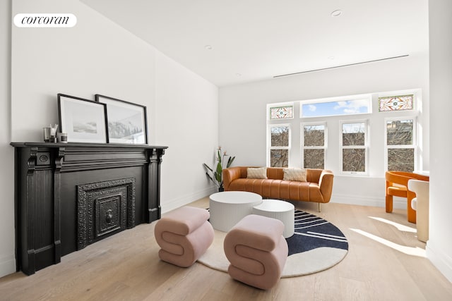 living room featuring baseboards, a fireplace, visible vents, and wood finished floors