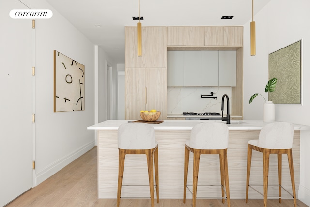 kitchen featuring decorative backsplash, a kitchen breakfast bar, modern cabinets, and light countertops