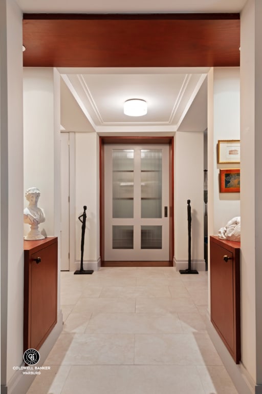 hall with light tile patterned floors and crown molding