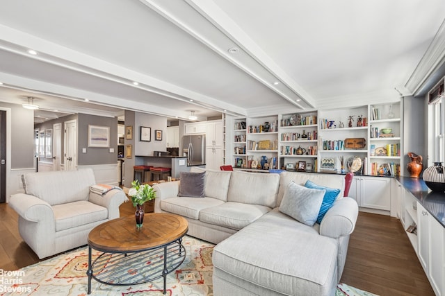 living area with dark wood-type flooring, recessed lighting, beam ceiling, and a wainscoted wall