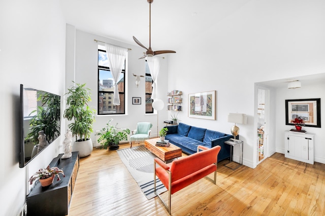 living room with baseboards, wood-type flooring, and a ceiling fan