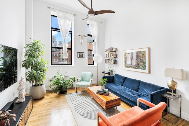 living room with baseboards, wood finished floors, and a ceiling fan