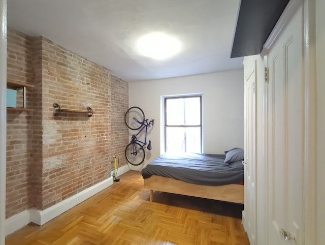 bedroom featuring baseboards and brick wall