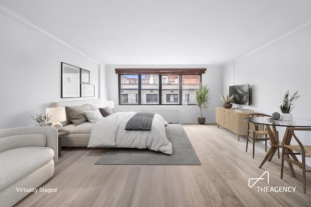 bedroom with ornamental molding and wood finished floors