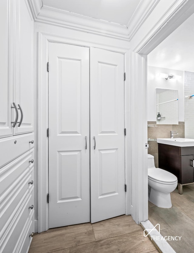 bathroom featuring toilet, crown molding, vanity, and wood finished floors