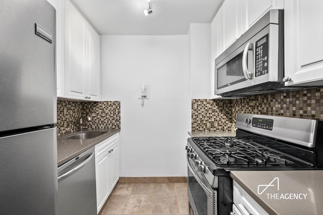 kitchen featuring stainless steel appliances, a sink, white cabinets, and baseboards