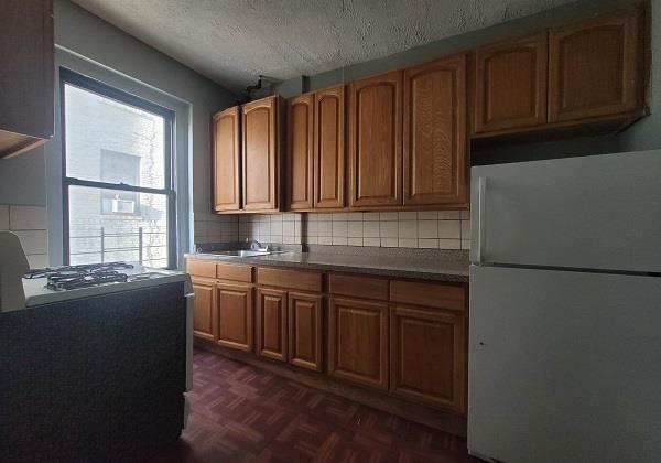 kitchen featuring white fridge, decorative backsplash, a textured ceiling, and dark parquet flooring