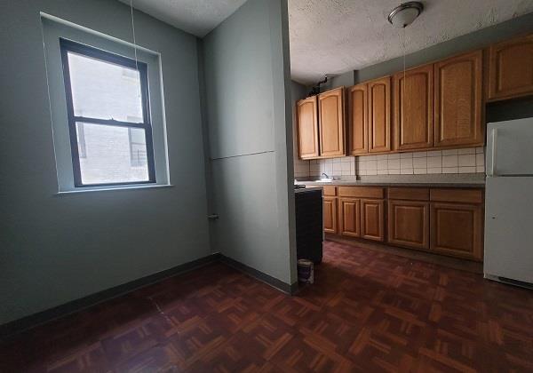 kitchen with brown cabinets, tasteful backsplash, freestanding refrigerator, a textured ceiling, and baseboards