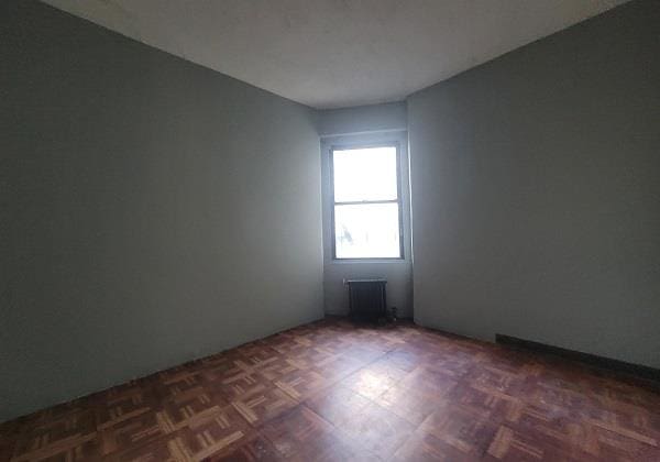 empty room with radiator and dark parquet flooring