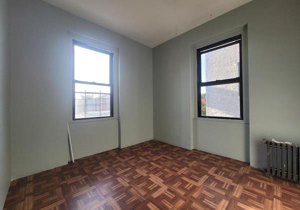 unfurnished room with dark parquet flooring and radiator heating unit