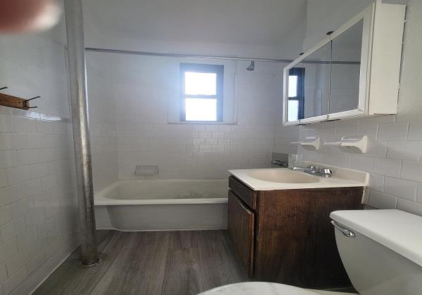 full bathroom with tile walls, vanity, tiled shower / bath, and toilet