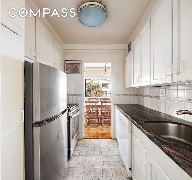 kitchen with appliances with stainless steel finishes, white cabinetry, tasteful backsplash, and sink