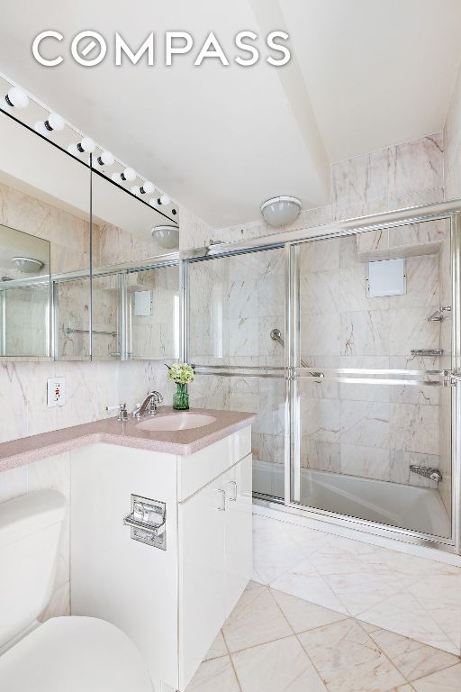 bathroom with tile walls, toilet, vanity, and walk in shower