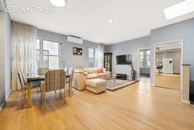 living area with recessed lighting, a skylight, baseboards, light wood finished floors, and a wall mounted air conditioner