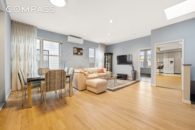 living room with a skylight, baseboards, a wall unit AC, light wood-style floors, and recessed lighting