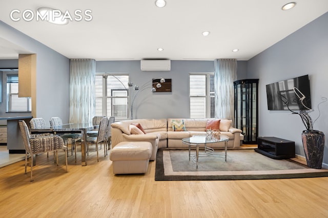 living room with a healthy amount of sunlight, wood finished floors, and a wall unit AC