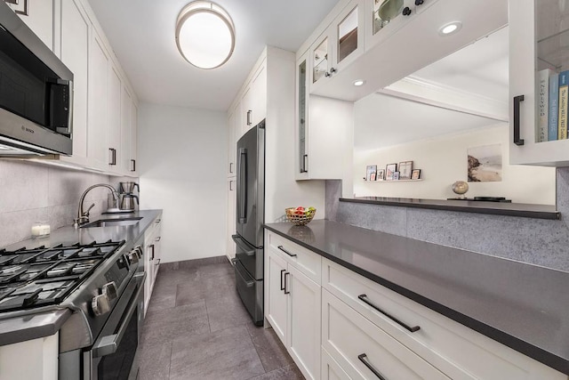 kitchen featuring stainless steel appliances, a sink, glass insert cabinets, and white cabinetry