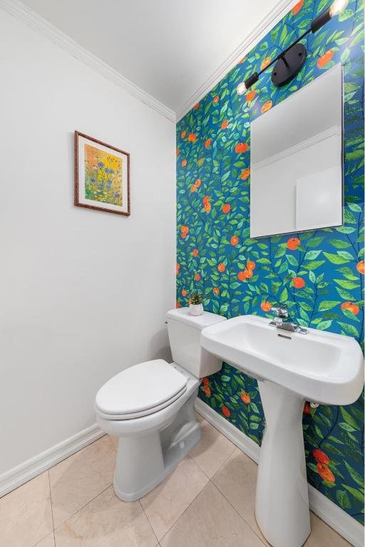 bathroom featuring toilet, baseboards, ornamental molding, and tile patterned flooring