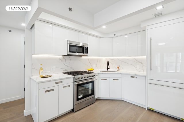 428 E 9th St Unit 703, New York City, NY 11218 - kitchen with appliances with stainless steel finishes, a sink, modern cabinets, white cabinets, and light wood-style floors