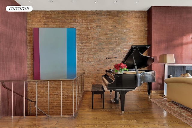 sitting room featuring wood finished floors and brick wall