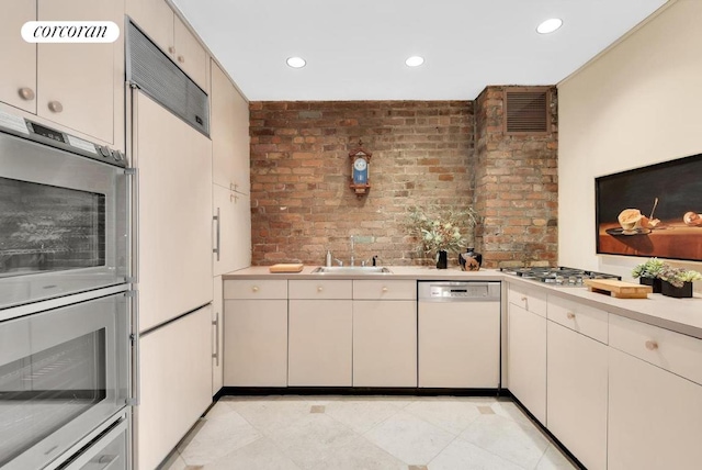 kitchen featuring sink, stainless steel appliances, and brick wall