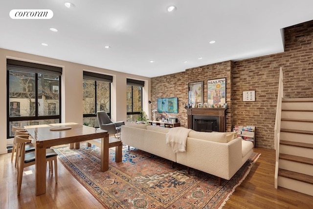living room featuring brick wall, wood-type flooring, visible vents, and recessed lighting