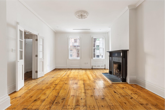 46 Perry St, New York City, NY 10014 - unfurnished living room with crown molding, light wood finished floors, a fireplace with raised hearth, and a baseboard radiator