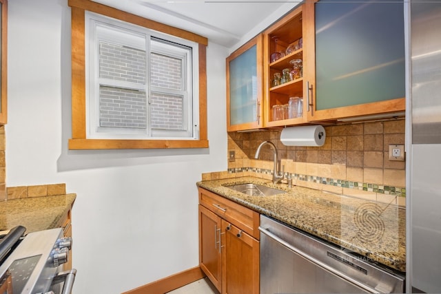 kitchen with tasteful backsplash, glass insert cabinets, appliances with stainless steel finishes, stone counters, and a sink