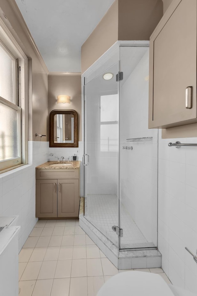14 Sutton Pl S Unit 13F, New York City, NY 10022 - bathroom featuring tile walls, vanity, a stall shower, tile patterned flooring, and wainscoting
