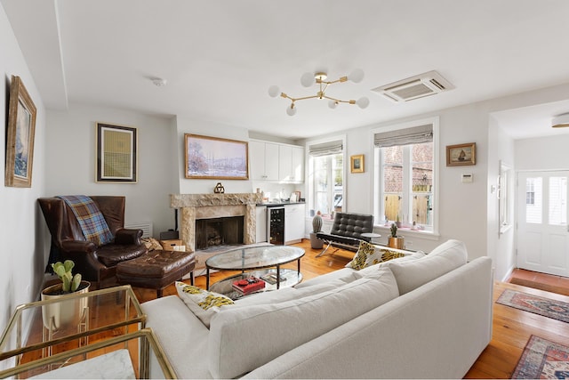 living room featuring wine cooler, light wood-type flooring, and a premium fireplace