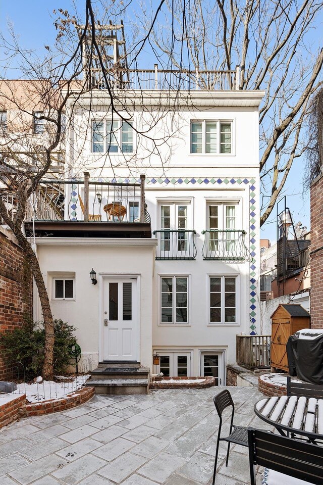 back of property with a patio, stucco siding, entry steps, a balcony, and a fire pit