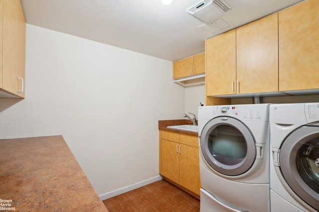 laundry area with cabinet space, baseboards, visible vents, separate washer and dryer, and a sink