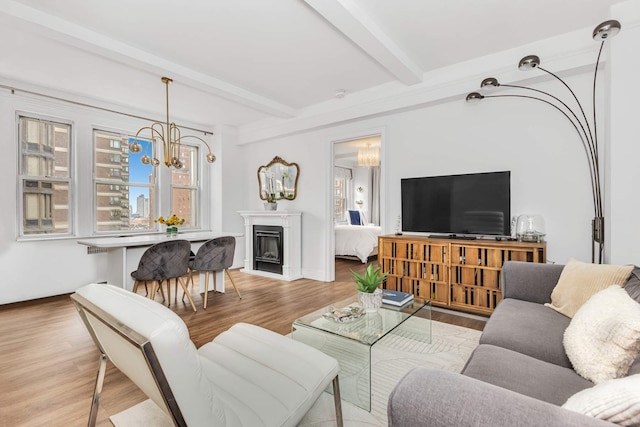 living area with an inviting chandelier, beam ceiling, a fireplace, and wood finished floors
