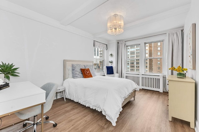 400 E 59th St Unit 9G, New York City, NY 10022 - bedroom featuring radiator heating unit, wood finished floors, a chandelier, a desk, and beam ceiling