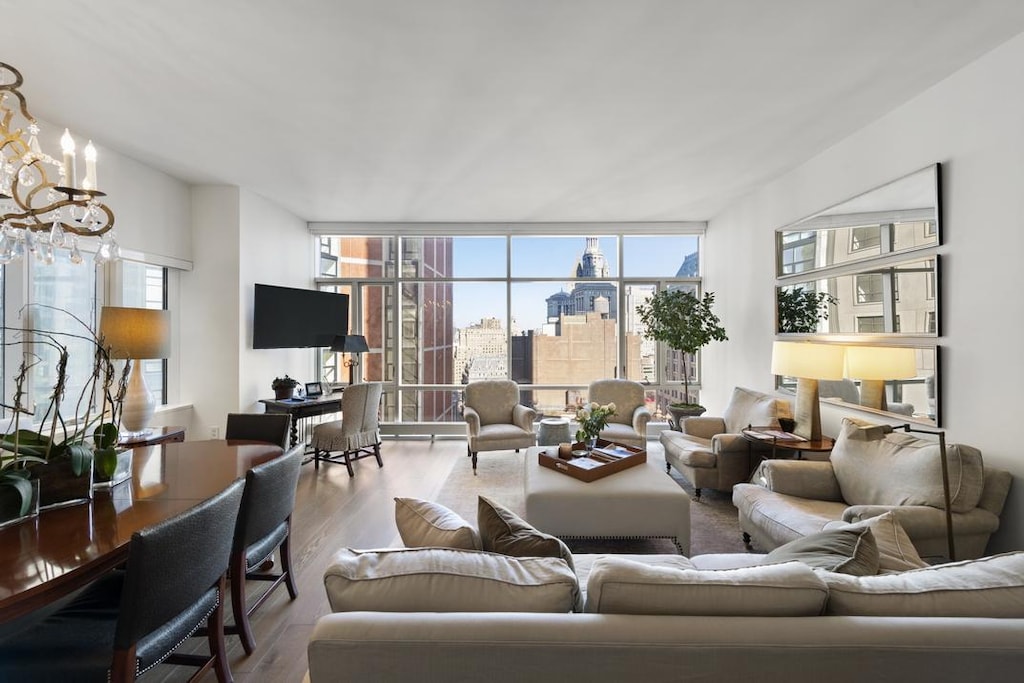 living area with a notable chandelier, a wall of windows, and wood finished floors