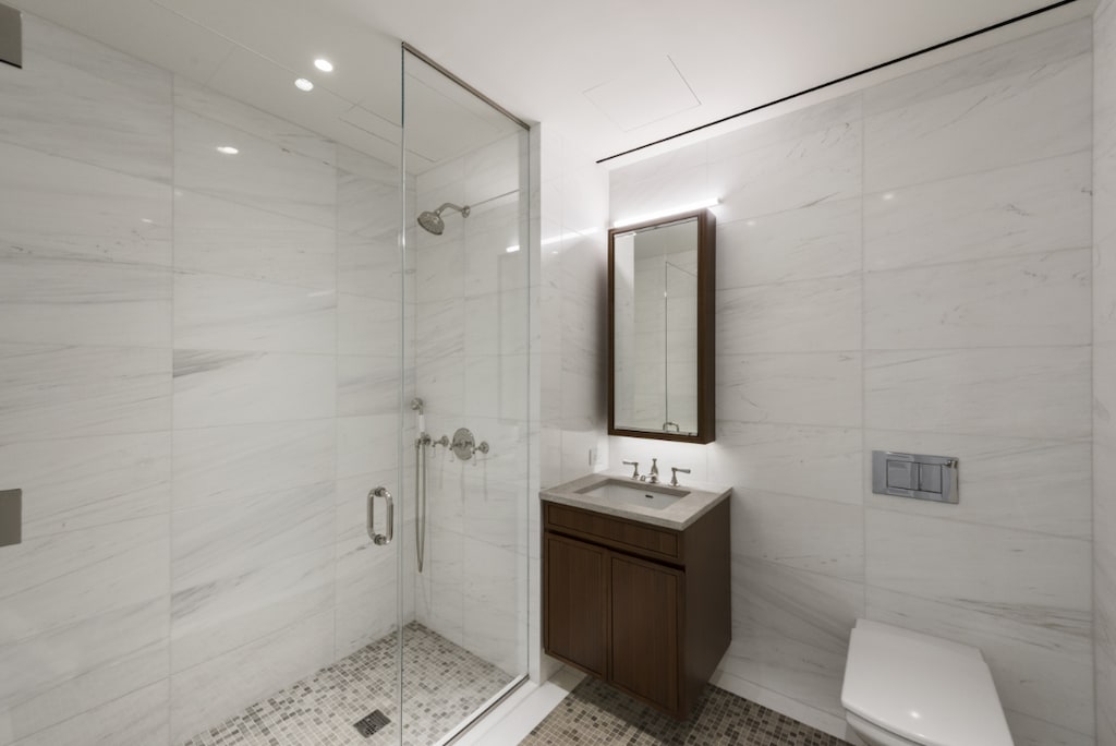 full bath with tile walls, a stall shower, vanity, toilet, and recessed lighting