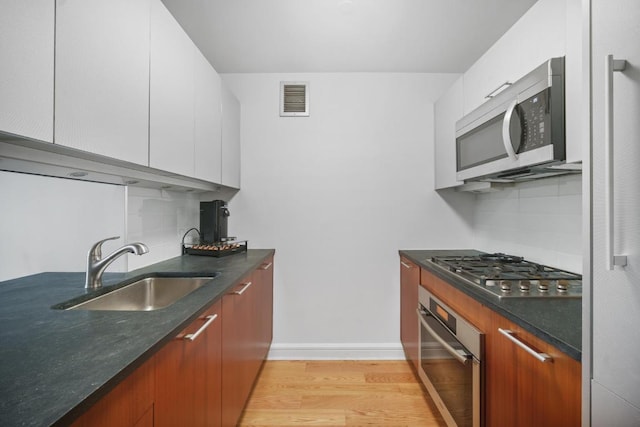 kitchen with white cabinetry, appliances with stainless steel finishes, sink, and tasteful backsplash