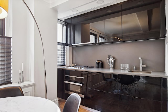 bar with a sink, appliances with stainless steel finishes, ornamental molding, and wood finished floors