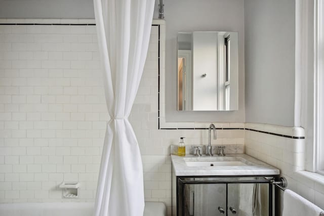 full bath featuring tile walls, shower / bath combo with shower curtain, and vanity