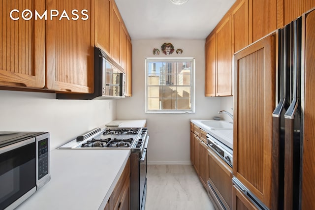 311 E 71st St Unit 8G, New York City, NY 10021 - kitchen featuring stainless steel appliances, light marble finish floors, light countertops, and brown cabinets
