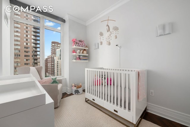 bedroom with a crib, baseboards, a view of city, and ornamental molding