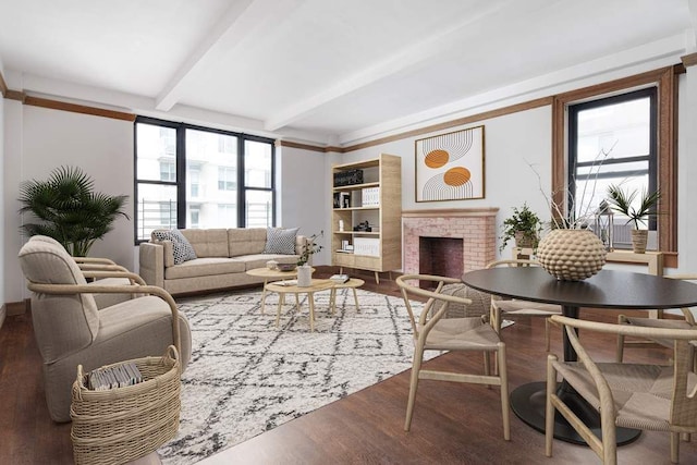 living room featuring beam ceiling, a brick fireplace, and wood finished floors