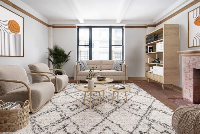 living area with beamed ceiling, a fireplace, baseboards, and wood finished floors