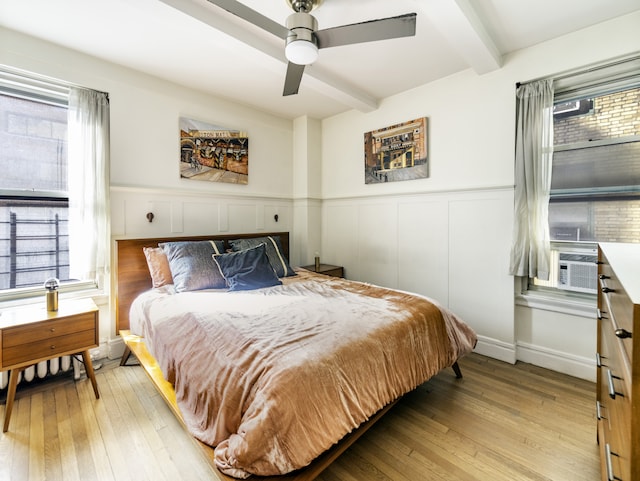 325 W 45th St Unit 404, New York City, NY 10036 - bedroom with light wood finished floors, a wainscoted wall, and beam ceiling