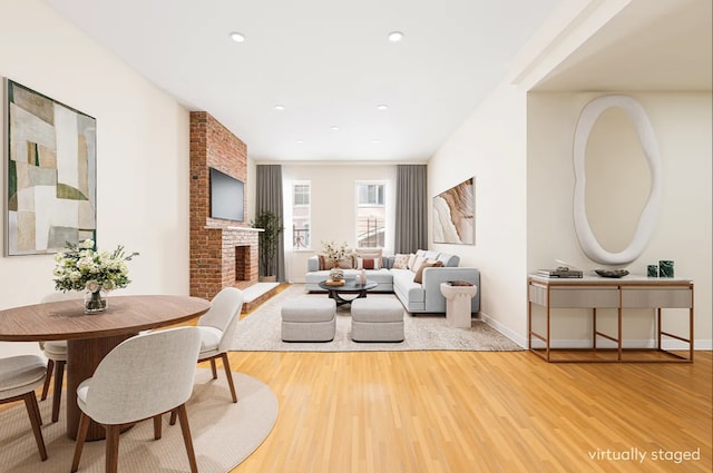 living area with wood finished floors, a brick fireplace, baseboards, and recessed lighting