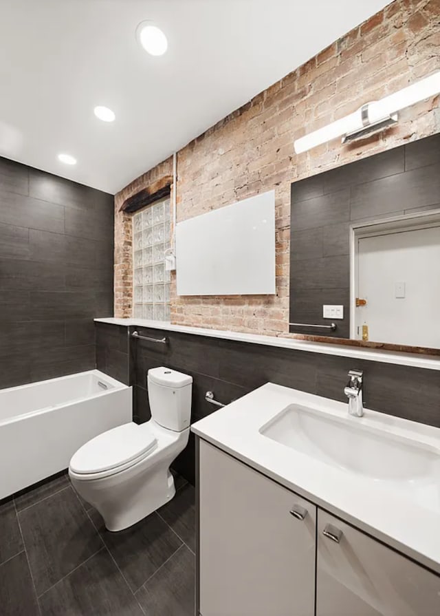 bathroom with toilet, a tub, vanity, recessed lighting, and tile walls