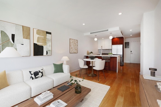 living room with recessed lighting, visible vents, and light wood finished floors