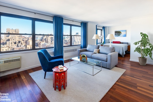 living area with a view of city, a wall unit AC, radiator, hardwood / wood-style floors, and baseboards