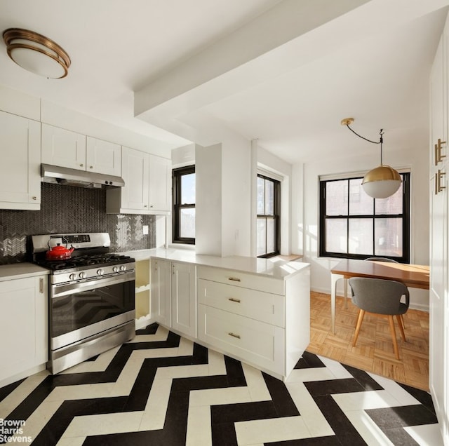 kitchen with white cabinetry, decorative light fixtures, stainless steel gas range oven, light parquet flooring, and decorative backsplash