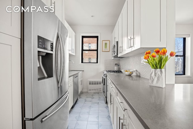 kitchen with backsplash, appliances with stainless steel finishes, white cabinets, and light tile patterned floors